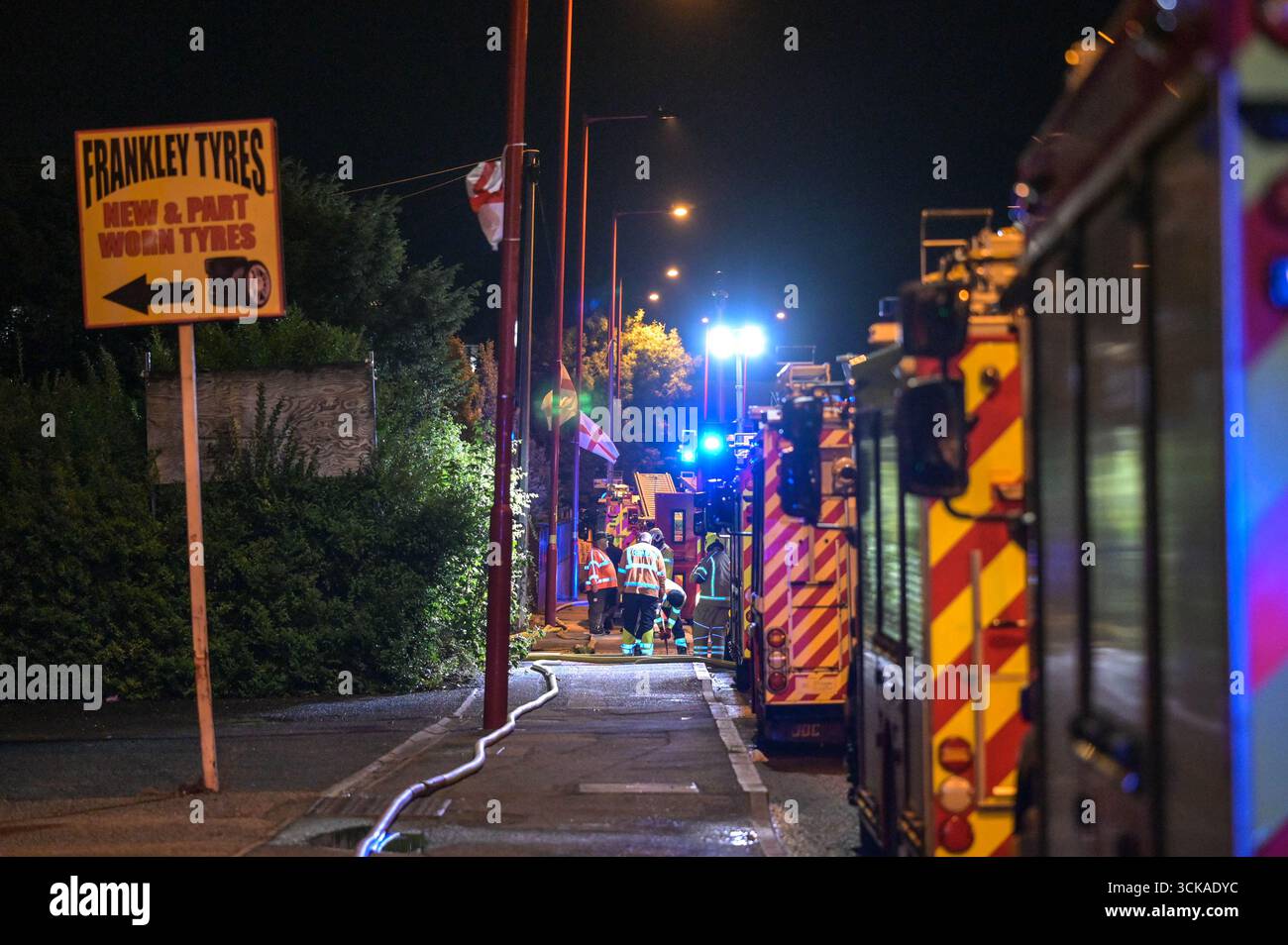 Longbridge, Birmingham, 11. September 2025. Mehr als 60 Feuerwehrleute sind in den frühen Morgenstunden des Donnerstags bei einem großen Brand in Longbridge, Birmingham, anwesend. Die Flamme hat Frankley Tyre Lagerhaus auf dem alten Gelände des MG Rover West Works erobert. Zwölf Feuerwehrfahrzeuge, zwei hydraulische Plattformen, die Vorfallskommando und verschiedene andere Ressourcen der Polizei, Cadent und des National Grid waren anwesend. Flammen leckten das Gebäude ab, als Wände einstürzten und die Feuerwehr Wasser mit Schläuchen besprühte. Die West Midlands Fire Service sagte in einem Beitrag auf Facebook: „Wir haben 12 Mannschaften, die bei einem Brand auf W anwesend sind Stockfoto