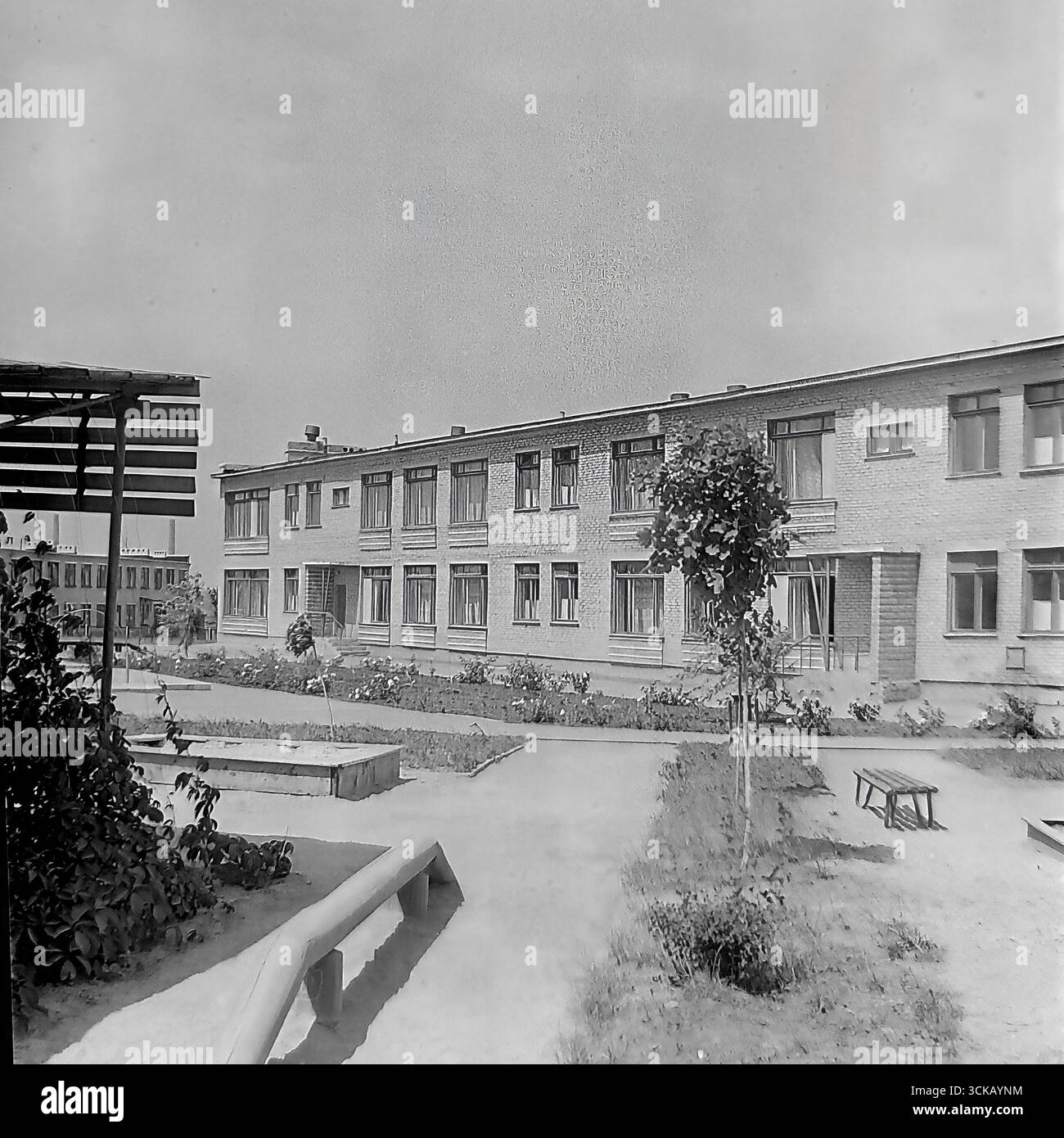 Ein typisches Kindergartengebäude mit Spielplatz in der Energiearbeiterstadt Mykolaivka (Ukrainische SSR) im Jahr 1970. Das Archivfoto zeigt eine soziale Einrichtung, die für die Kinder der Sloviansk GRES-Arbeiter gebaut wurde. Die Szene mit einem Sandkasten, einer Veranda und einem landschaftlich gestalteten Bereich ist ein Beleg für die entwickelte soziale Infrastruktur sowjetischer Industriestädte und spiegelt die Sorge des Staates für die jüngere Generation während der Ära der Stagnation wider Stockfoto