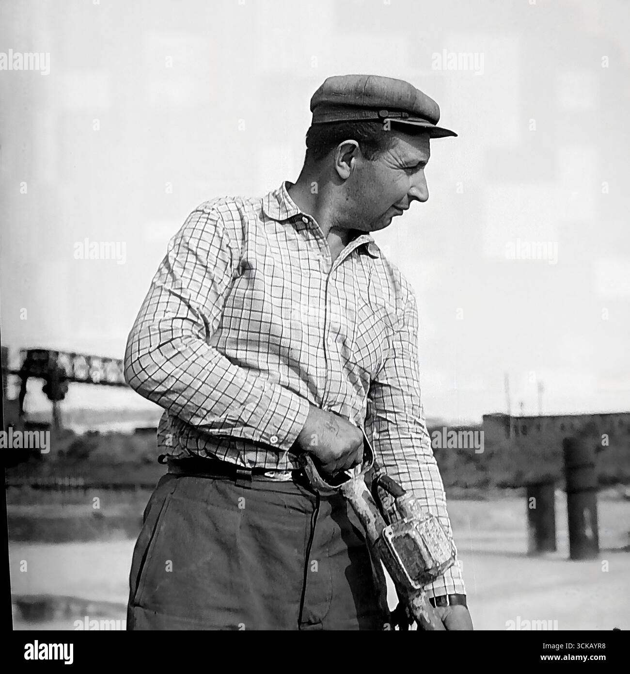 Ein sowjetischer Betonarbeiter auf der Baustelle der Slowiansk GRES in Mykolaivka, Ukrainische SSR, 1970. Das Archivfoto zeigt einen Mann, der die Betonmischung während des Gießens eines Fundaments mit einem Betonvibrator komprimiert. Dieses Produktionsporträt ist eine Hommage an die harte körperliche Arbeit der Baumeister, deren Hände die Riesen der sowjetischen Energie geschaffen haben, und es vermittelt die Atmosphäre eines "großen Bauprojekts des Kommunismus". Stockfoto
