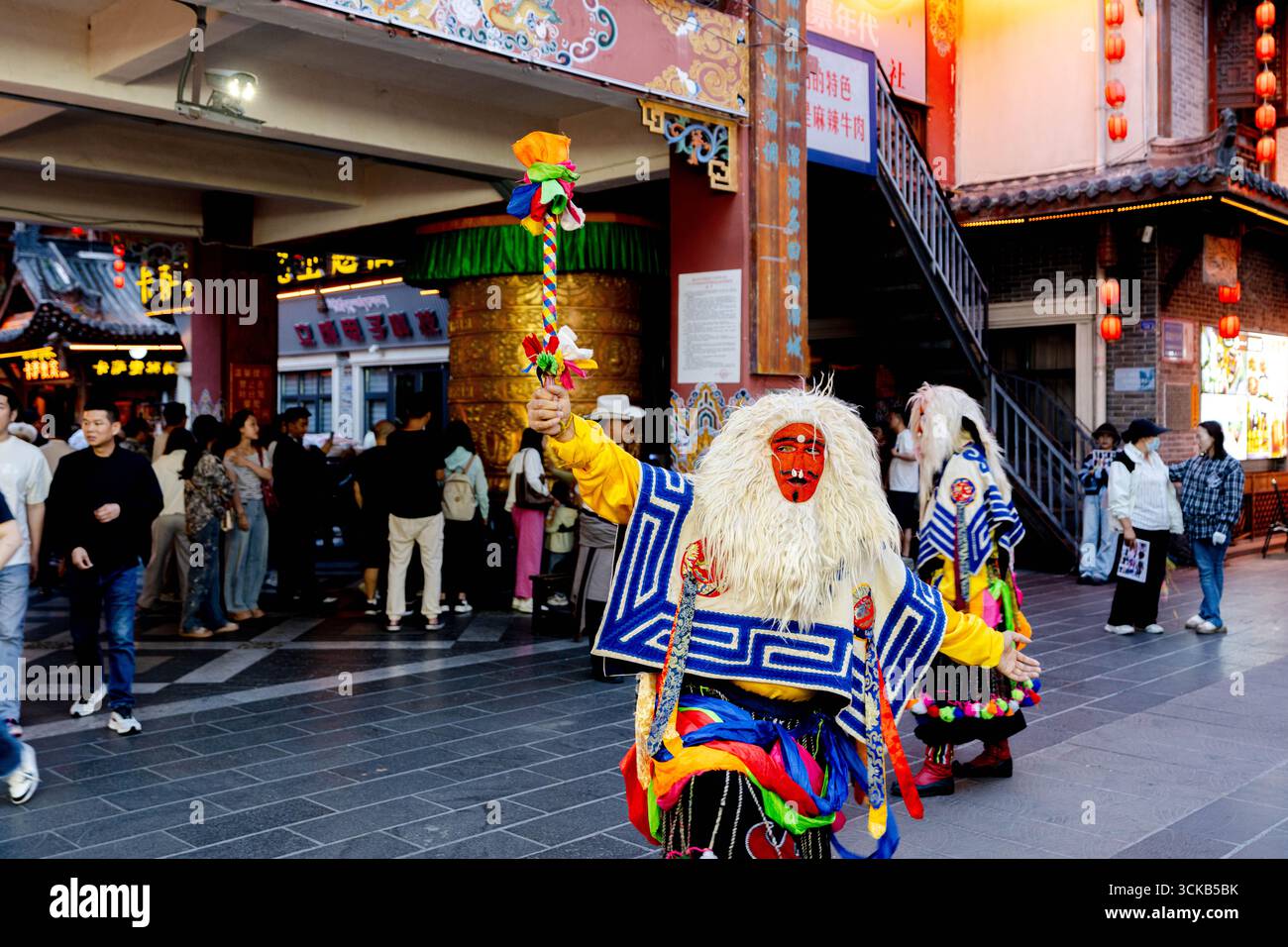 Ein tibetischer Operndarsteller in traditioneller Maske und Tracht unterhält die Menge in der berühmten Stadt Liu Liu in Kangding während der Abenddämmerung. Stockfoto