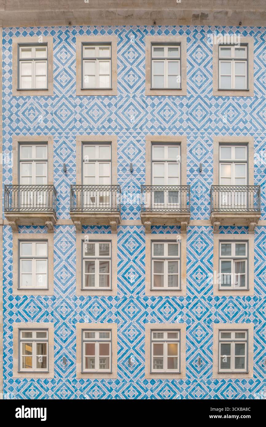 Geometrische blau-weiß gekachelte Fassade mit symmetrischen Fenstern und Balkonen in Porto, Portugal. Fliesen mit Rautenmuster, portugiesische Architektur Stockfoto