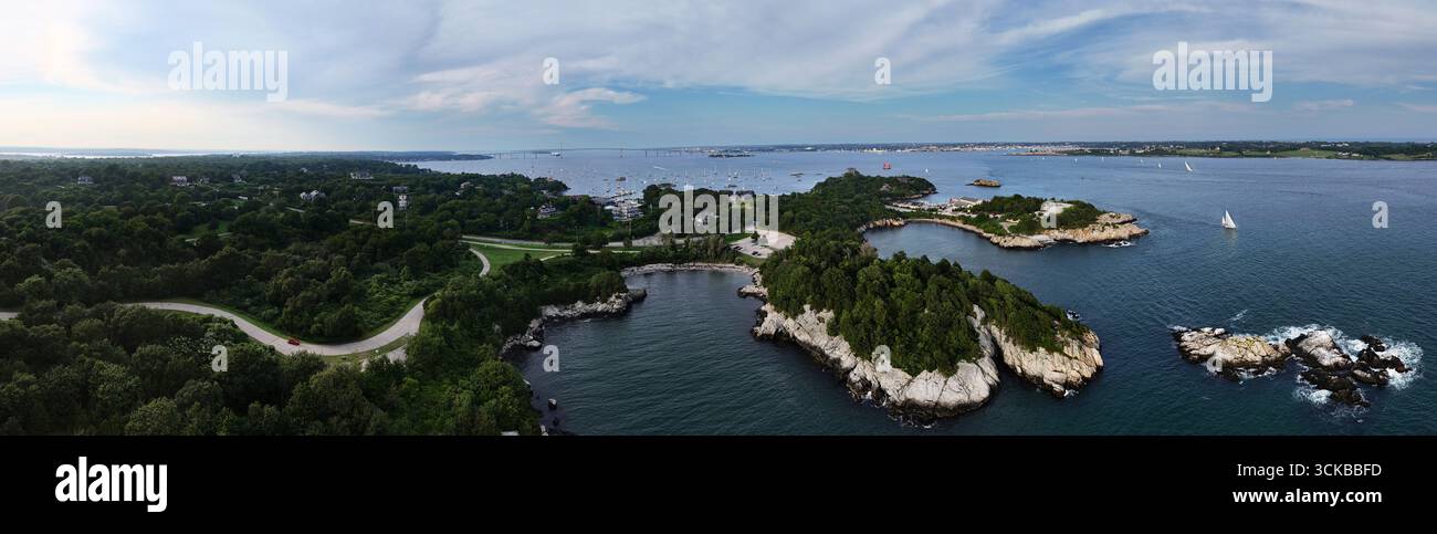 Aus der Vogelperspektive auf die felsige Küste trifft auf das tiefblaue Meer, im Kontrast zu den üppigen grünen Wäldern von Fort Wetherill, Jamestown, Rhode Island, USA. Stockfoto