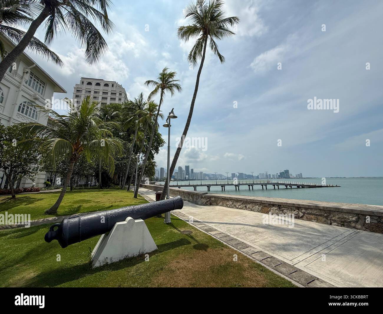 Eine Kanone in den Gärten, die auf das Meer zeigt, vor dem Eastern & Oriental (E&O) Hotel in Goerge Town, Hauptstadt Penang in Malaysia, - Smartphone-aufgenommenes Stockfoto