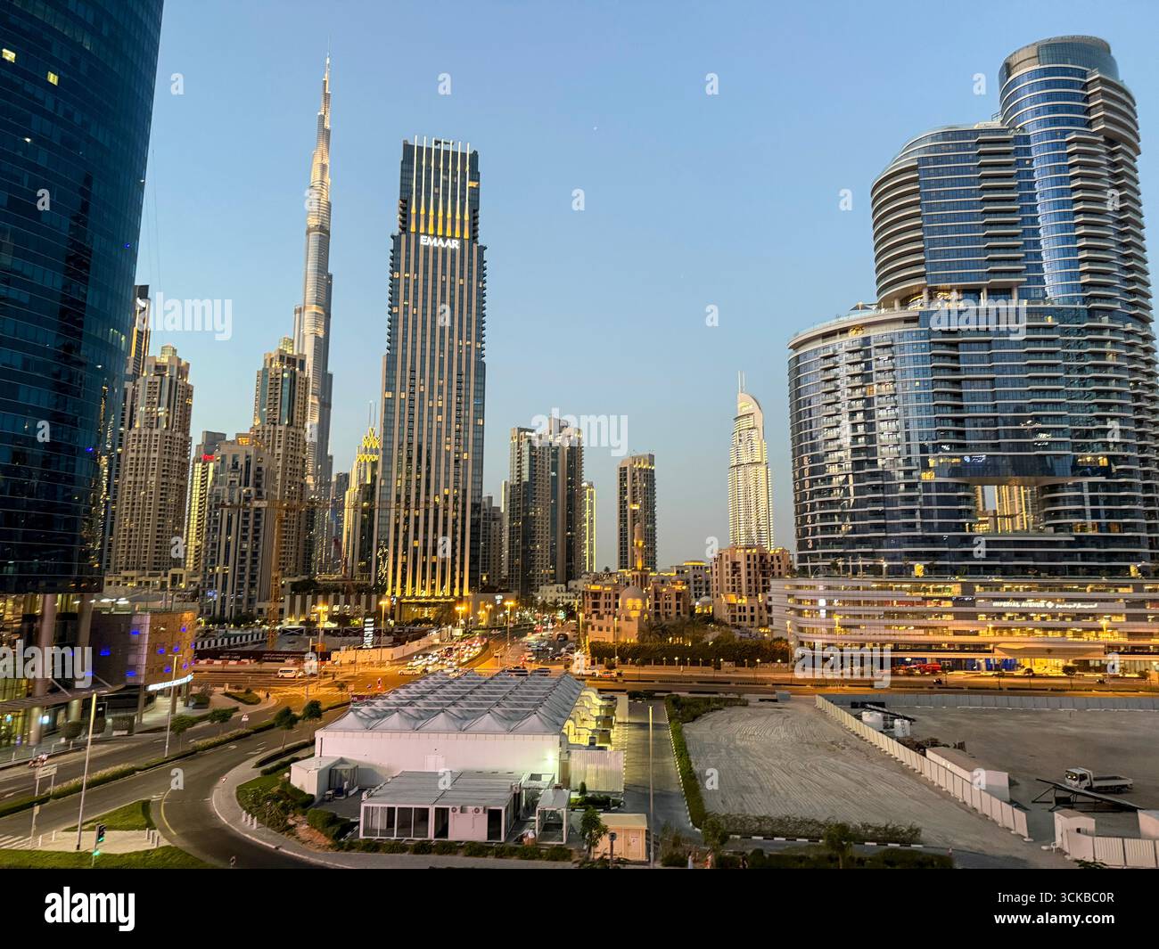 Wenn die Sonne untergeht, erwachen die Lichter über der Innenstadt von Dubai in den Vereinigten Arabischen Emiraten zum Leben. Die Skyline des dünnen, bekannten Burj Khalifa Schlepptau - Smartphone-aufgenommenes Stockfoto