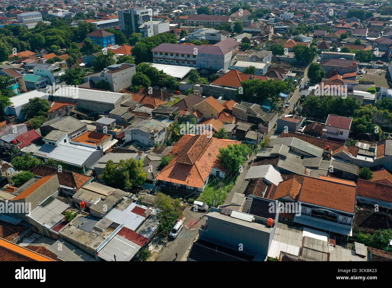 Aus der Vogelperspektive auf ein dicht besiedeltes Stadtgebiet mit einer Mischung aus Wohn- und Geschäftsgebäuden, mit verschiedenen Dachstilen und Grünflächen Stockfoto