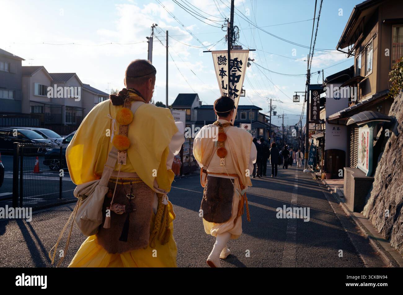 Mönchsfiguren in zeremoniellen Gewändern gehen während des Tōka Ebisu Festivals eine enge Straße in Kyoto hinunter Stockfoto