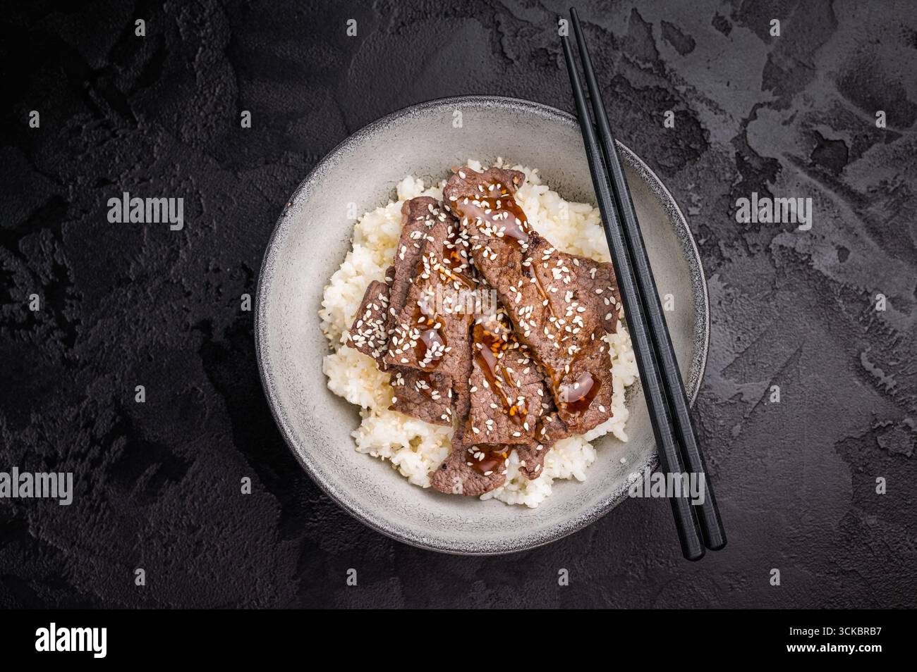 Yakiniku, Wagyu marmorierte Rindfleischstücke und Reis in einer Schüssel. Eine kulinarische Reise, die die Essenz der japanischen Grilltradition einfängt. Schwarzer Hintergrund. Stockfoto