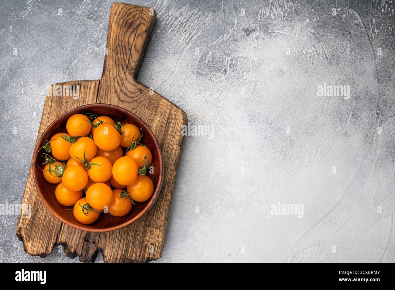 Frische kleine gelbe Kirschtomaten-Sortiment, Mini-Bio-Cocktail-Tomatenmischung. Grauer Hintergrund. Draufsicht. Stockfoto