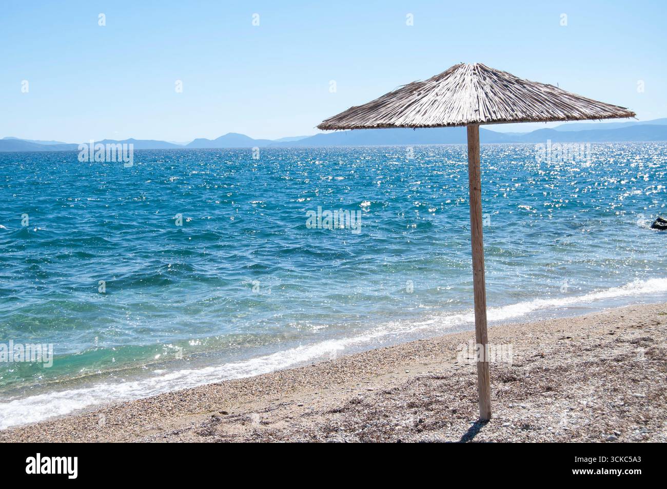 Ein Sonnenschirm am leeren Strand. Ein Meeresufer mit einem Regenschirm. Ein Seascape-Frame mit Kopierraum. Reise- und Tourismushintergrund. Stockfoto