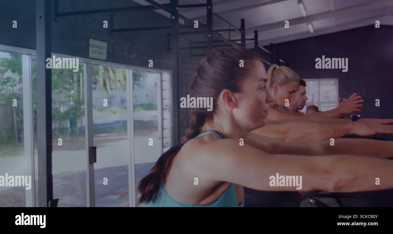 Ruderteilnehmer greifen Griffe in Tanks neben Glasfenstern im Fitnessraum mit Wasserflasche. Fitness, Training, Cardio, Sport, Bewegung, Stärke, Stockfoto