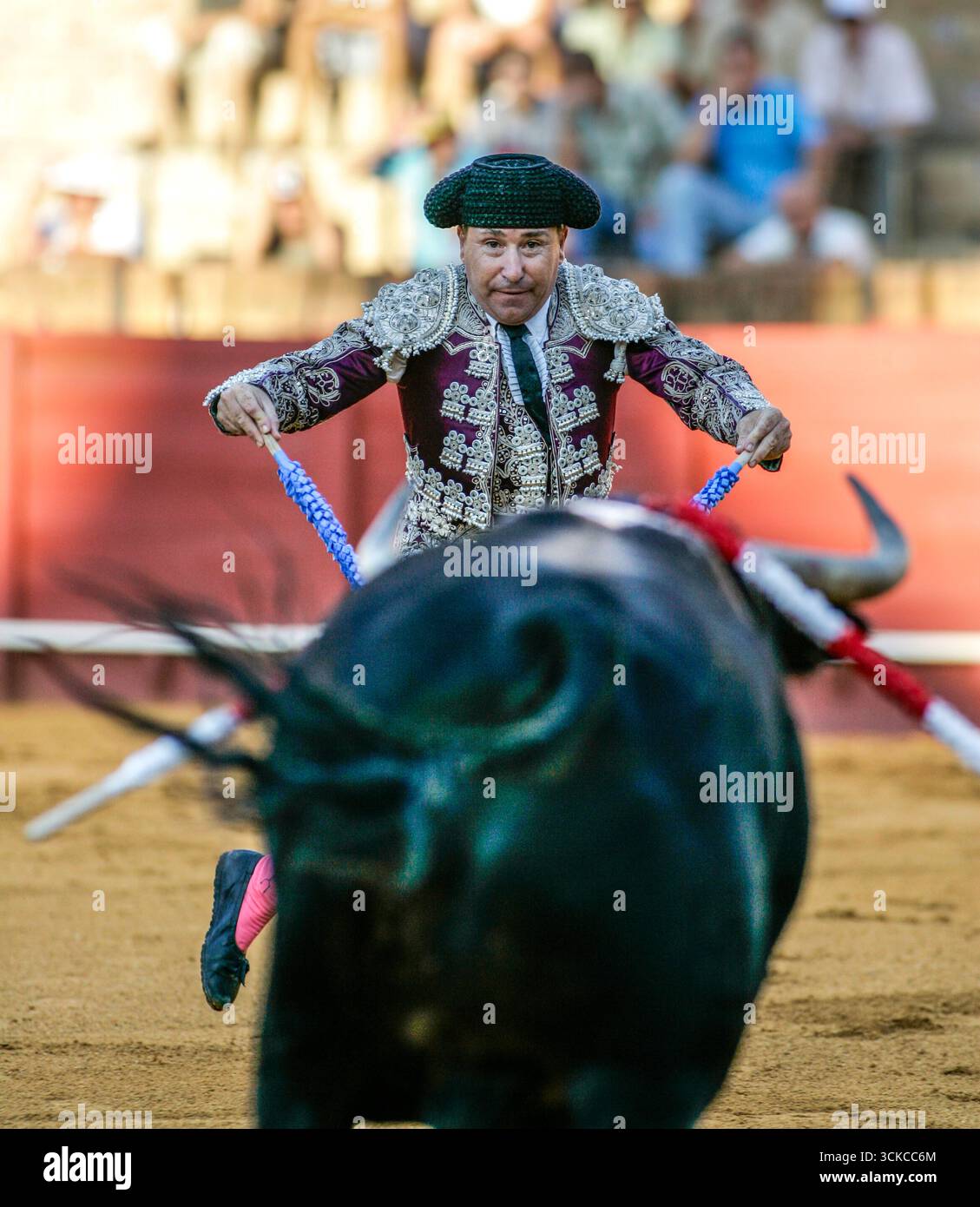 Sevilla, Spanien, 15. August 2007, in der Real Maestranza Stierkampfarena, Sevilla, steht ein Banderillero einem aufladenden Stier gegenüber, dessen Arme angehoben sind und die Kunst und Tensio verkörpern Stockfoto
