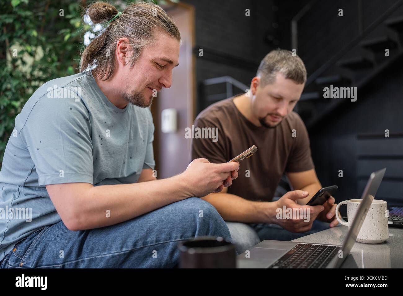 Zwangloses Meeting im modernen Café. Team von Programmierern, die digitalen Code in der Metaverse schreiben und zusammenarbeiten Stockfoto