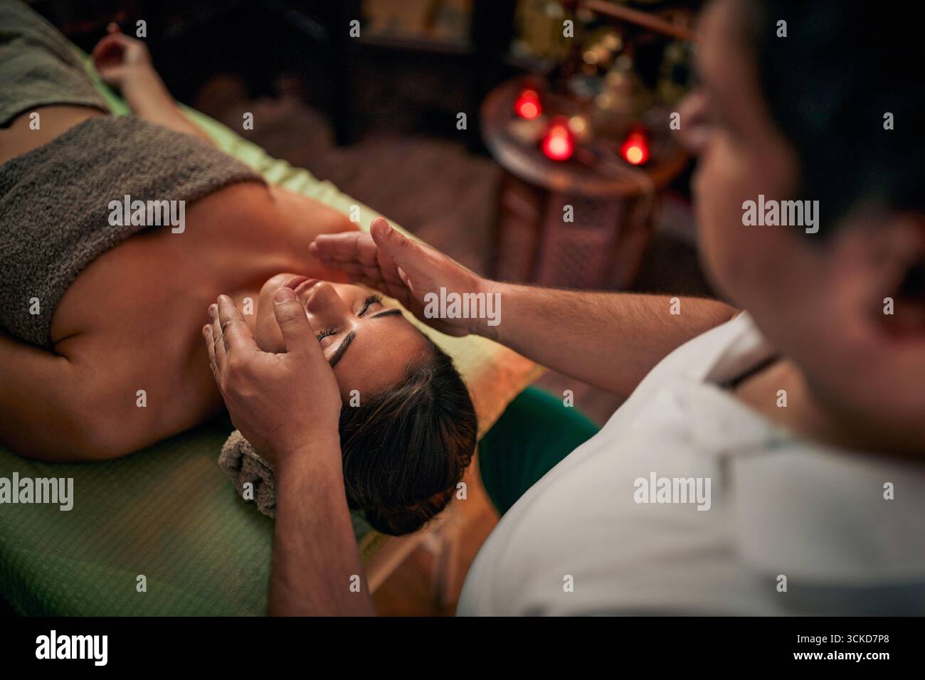 Junge Frau in ganzheitlicher Therapie in einem Heilbad. Männlicher Therapeut, der Reiki-Behandlung mit Bioenergie macht. Wellness, Lifestyle-Konzept. Stockfoto