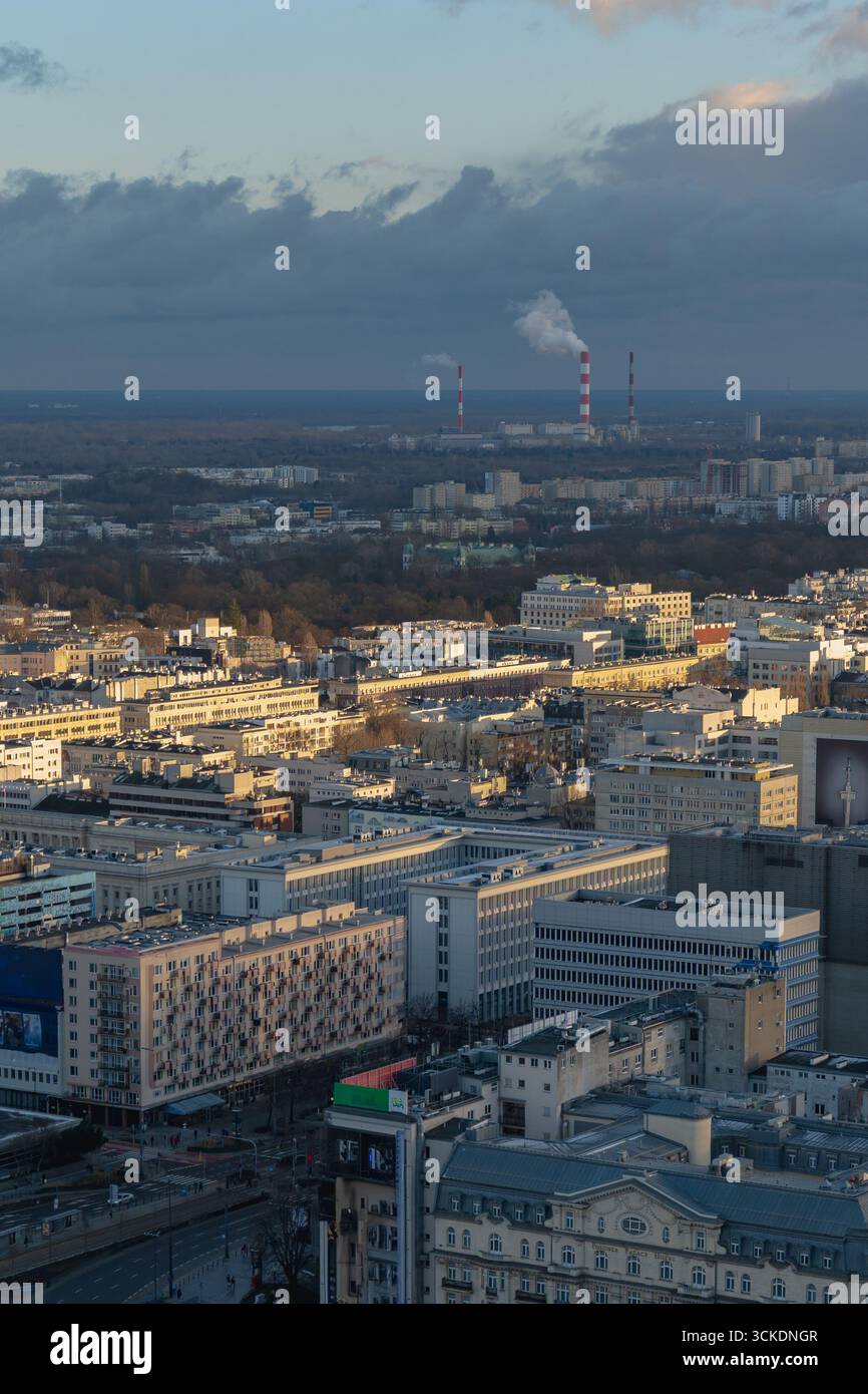 Erhöhter Blick auf Warschau, Polen, mit modernen und historischen Gebäuden, Industrieschornsteinen und städtischen Gebieten unter spätem Nachmittagslicht. Stockfoto