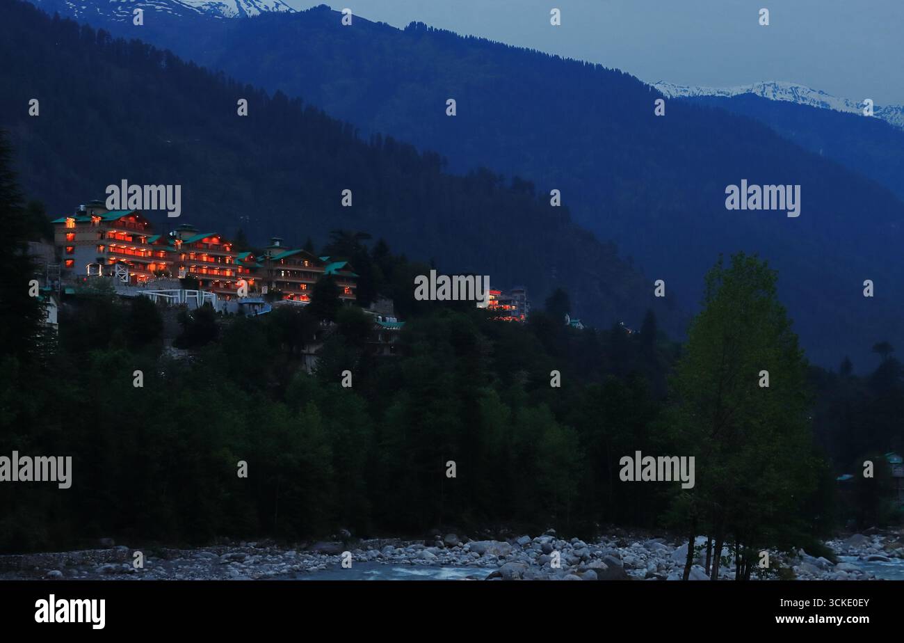 Panoramablick auf die Bergstation manali mit beleuchtetem Licht während der Dämmerung, schneebedeckte himalaya-Berge im Hintergrund, himachal pradesh, indien Stockfoto