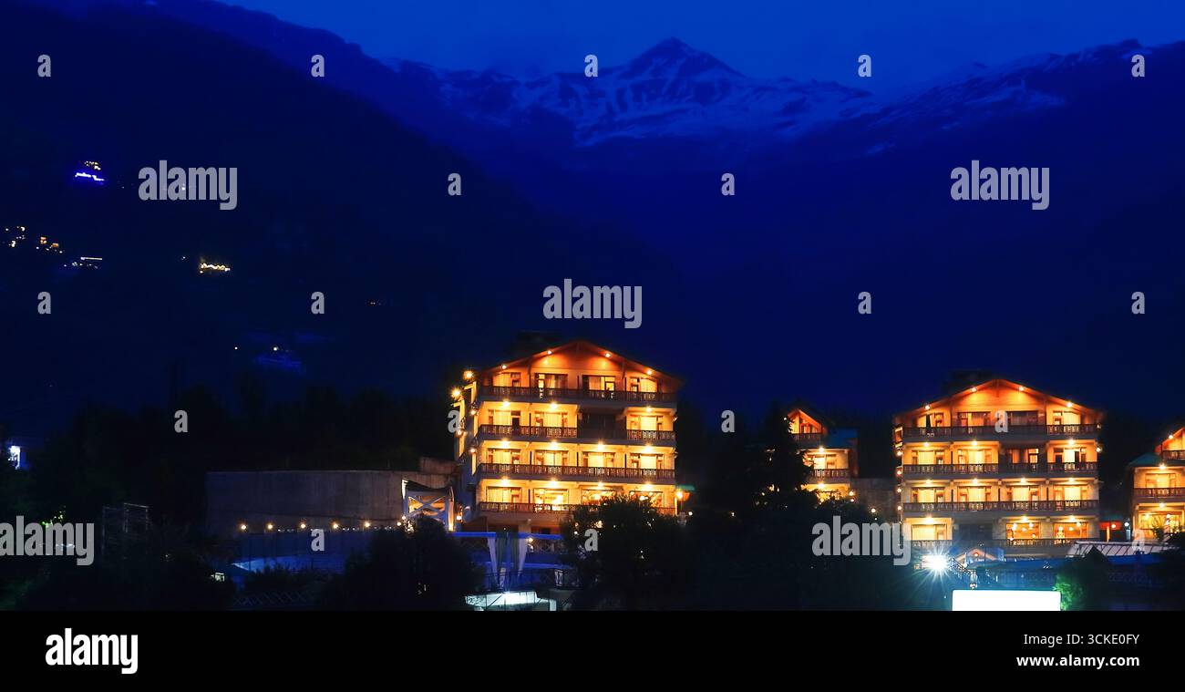 Panoramablick auf die Bergstation manali mit beleuchtetem Licht während der Dämmerung, schneebedeckte himalaya-Berge im Hintergrund, himachal pradesh, indien Stockfoto