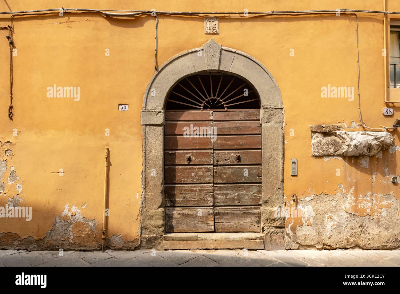 Eine alte Doppeltür in einer Via Dell Anfiteatro, einer engen Straße, in Lucca, Italien. Der Eingang zu Nummer 50, in dieser Straße. Stockfoto