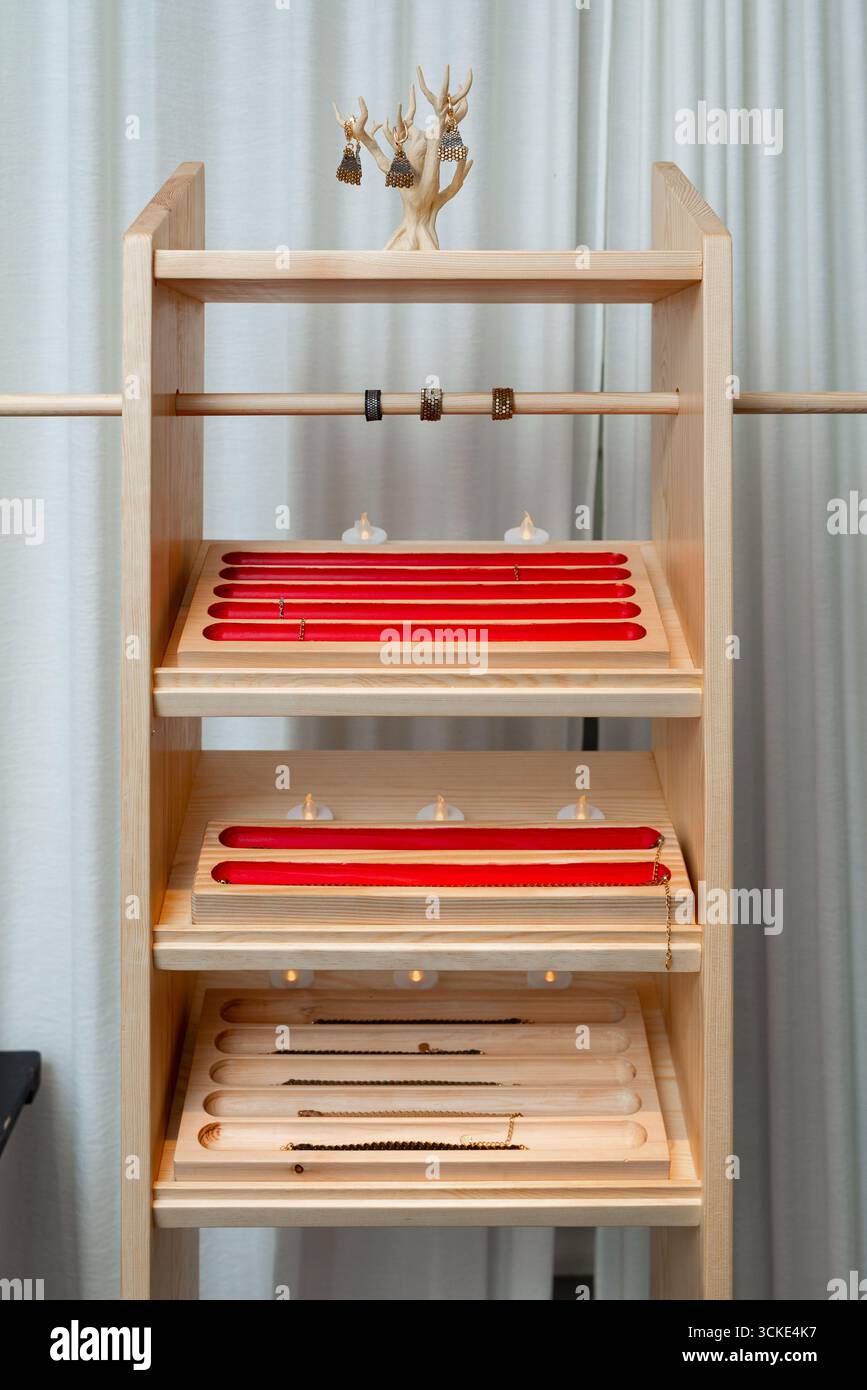 Minimalistisches Schmuckstück mit Armreifen und Halsketten auf Holzregalen. Stockfoto
