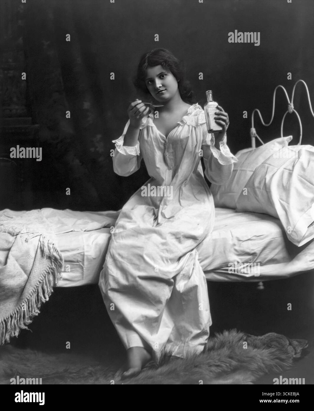 Frau auf dem Bett sitzt und die Löffel Medizin Stockfoto