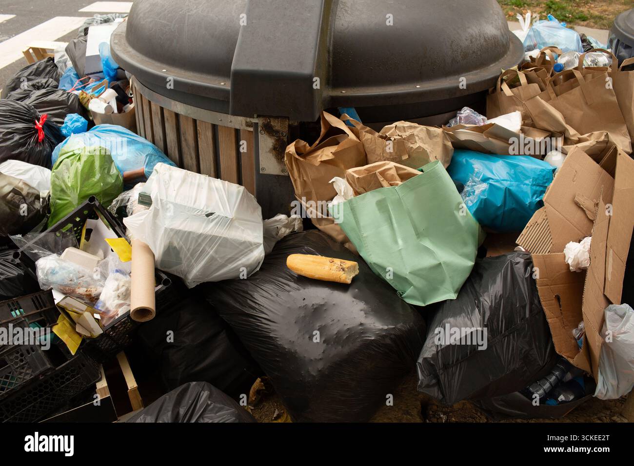 Eine Nahaufnahme eines kaputten Baguettes auf einem Stapel Müllsäcke, das Lebensmittelverschwendung und soziale Ungleichheit symbolisiert. Das Bild vermittelt ein kraftvolles Öko Stockfoto