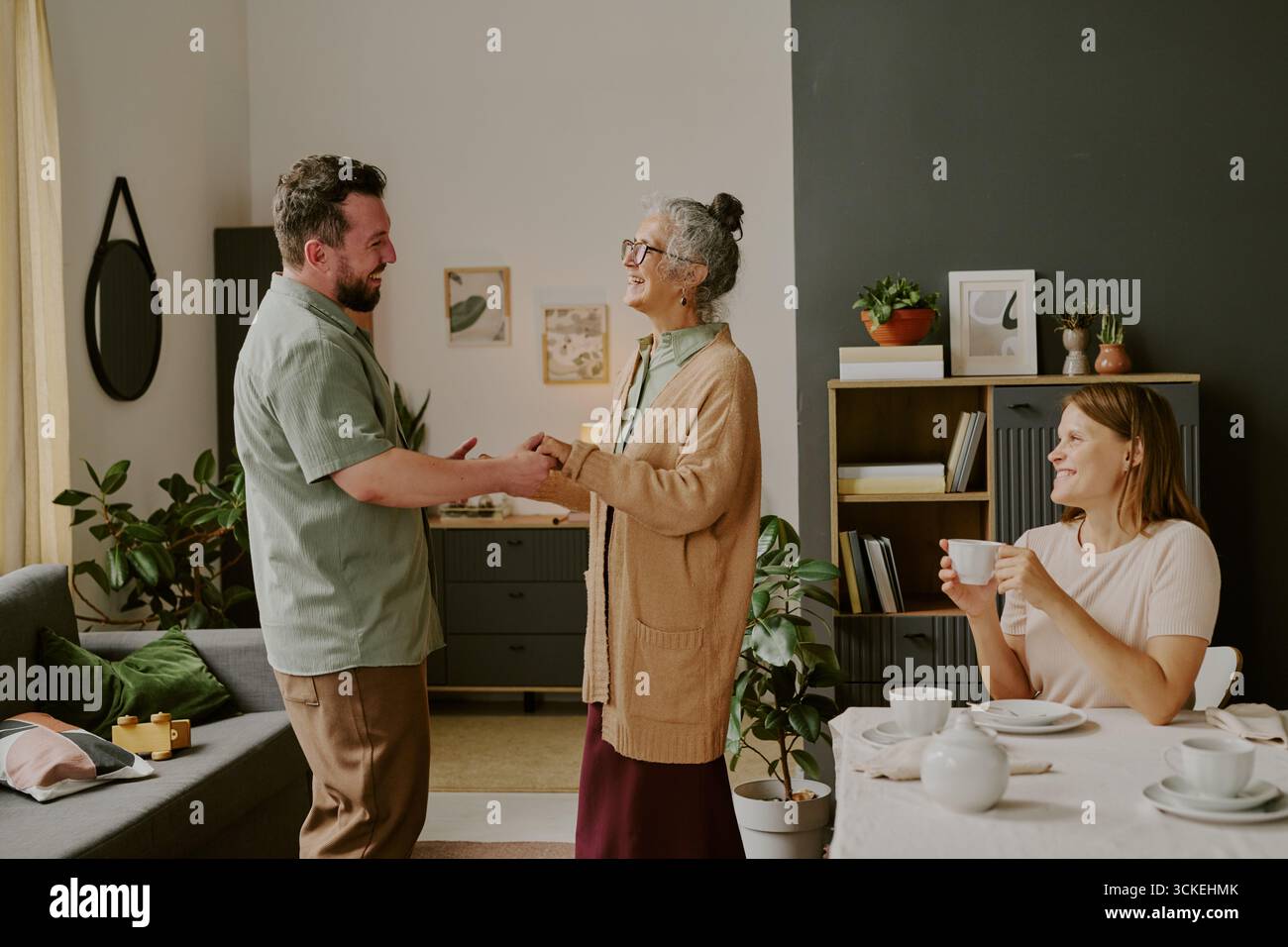 Ein Mann im mittleren Alter, der Hände hält und eine ältere kaukasische Frau lächelt Stockfoto