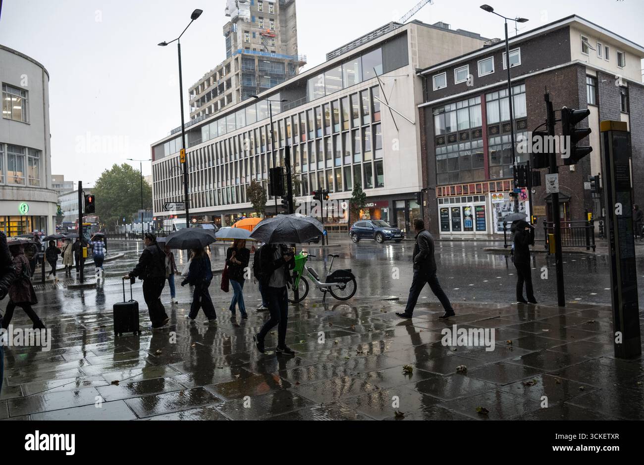 Bei starken Regenschauern im Herbst werden Pendler und Touristen am Nachmittag in Notting Hill, West london, England, Großbritannien, beobachtet Stockfoto