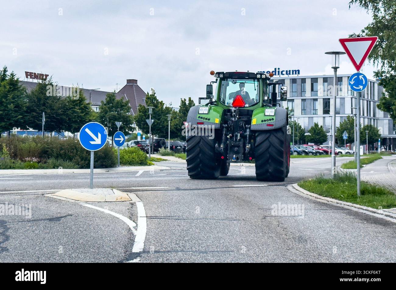 Marktoberdorf, Deutschland. Juli 2025. Green Modern Fendt Traktor, der auf einer Stadtstraße in der Nähe von Bäumen und einem modernen Gebäude navigiert und Landwirtschaft und Verkehr in einer städtischen Umgebung präsentiert. Eine Darstellung des Crossovers zwischen Landmaschinen und städtischer Infrastruktur am 24. Juli 2025 in Marktoberdorf, Bayern. Fotograf: ddp Images/STAR-Images Credit: ddp Media GmbH/Alamy Live News Stockfoto