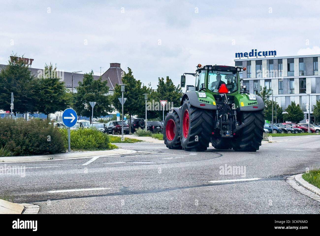 Marktoberdorf, Deutschland. Juli 2025. Green Modern Fendt Traktor, der auf einer Stadtstraße in der Nähe von Bäumen und einem modernen Gebäude navigiert und Landwirtschaft und Verkehr in einer städtischen Umgebung präsentiert. Eine Darstellung des Crossovers zwischen Landmaschinen und städtischer Infrastruktur am 24. Juli 2025 in Marktoberdorf, Bayern. Fotograf: ddp Images/STAR-Images Credit: ddp Media GmbH/Alamy Live News Stockfoto