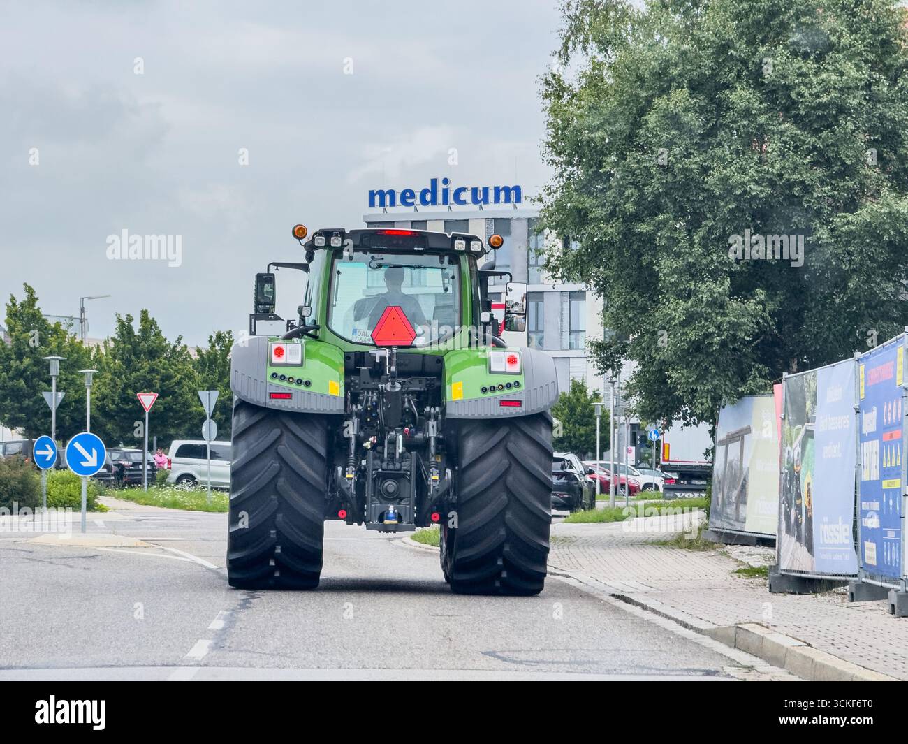Marktoberdorf, Deutschland. Juli 2025. Green Modern Fendt Traktor, der auf einer Stadtstraße in der Nähe von Bäumen und einem modernen Gebäude navigiert und Landwirtschaft und Verkehr in einer städtischen Umgebung präsentiert. Eine Darstellung des Crossovers zwischen Landmaschinen und städtischer Infrastruktur am 24. Juli 2025 in Marktoberdorf, Bayern. Fotograf: ddp Images/STAR-Images Credit: ddp Media GmbH/Alamy Live News Stockfoto