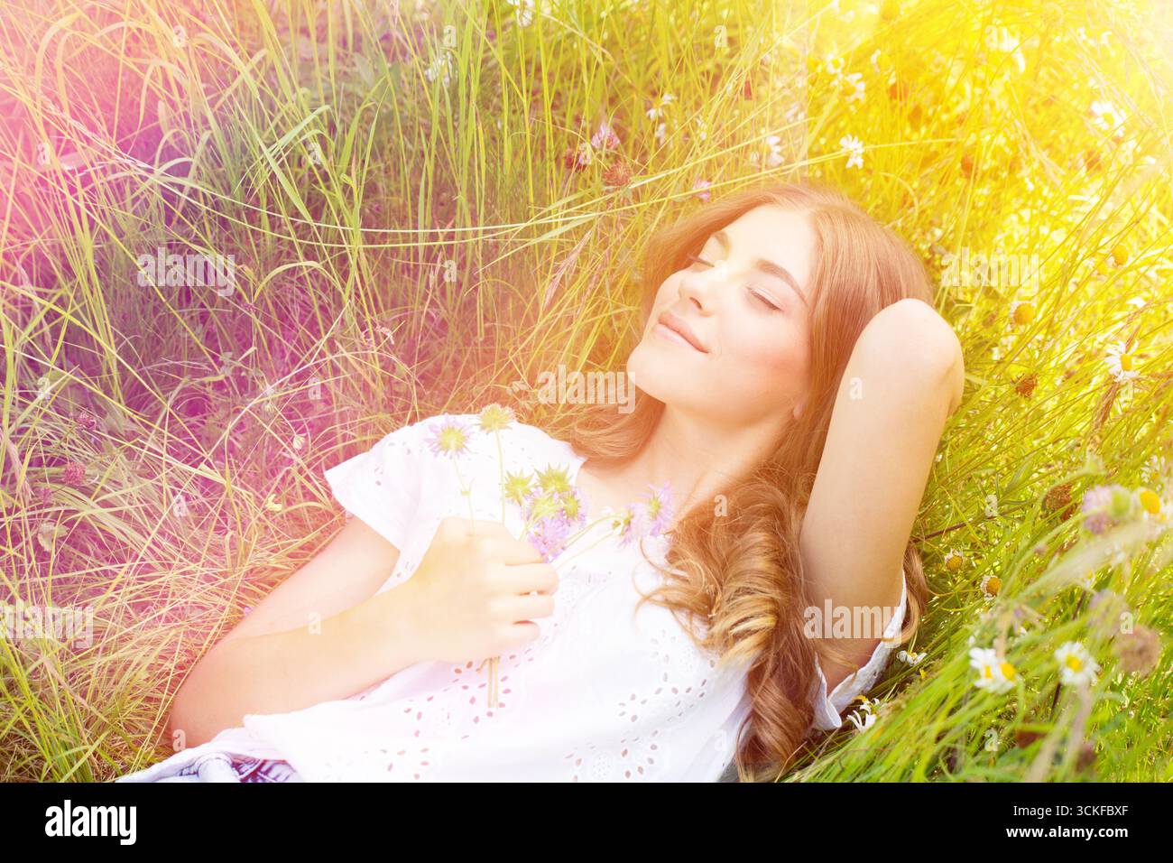 Eine junge Frau, die auf einer Blumenwiese liegt Stockfoto