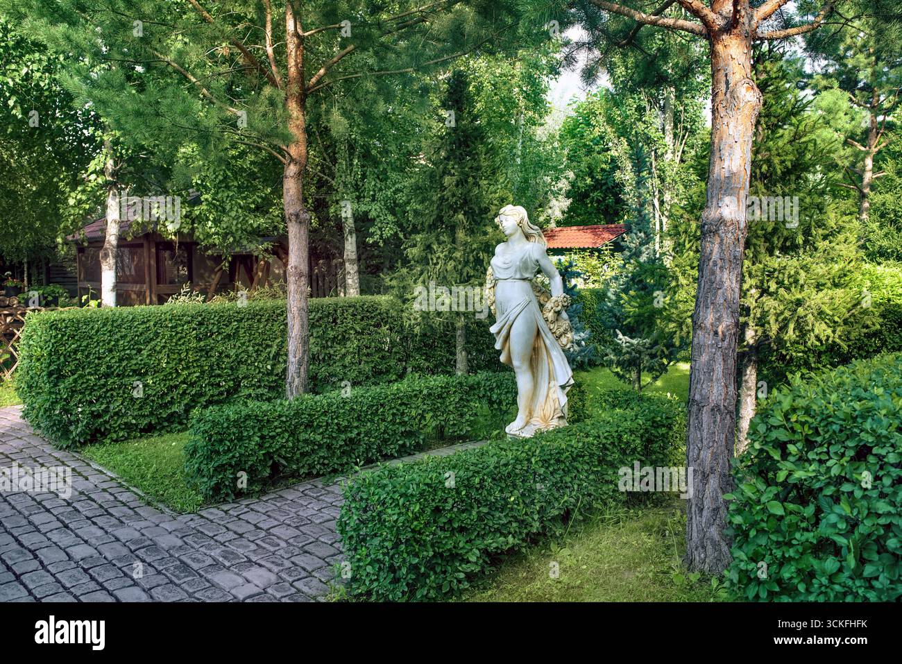 Eine wunderschöne Gartenlandschaft mit wunderschönen Rasenflächen, Statuen, Büschen und Bäumen. Stockfoto