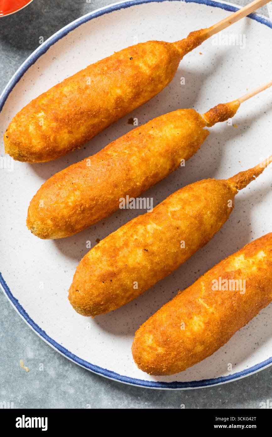 Süßer hausgemachter, gebratener Maishund auf einem Stock mit Senf und Ketchup Stockfoto