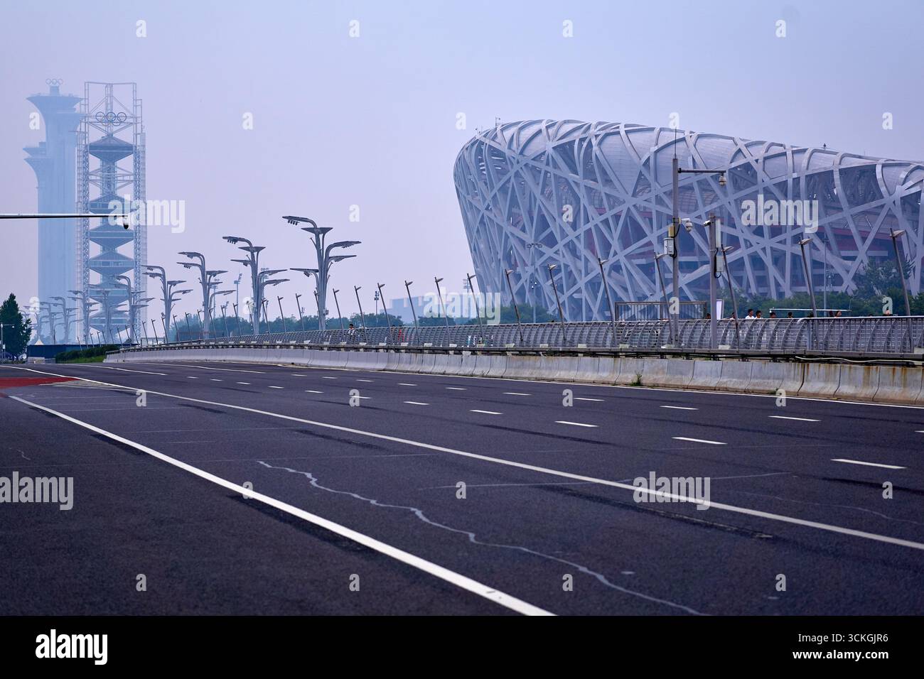 Blick auf eine leere Autobahn auf das Nationalstadion oder das Vogelnest und den Aussichtsturm des Olympischen Parks in Peking, China Stockfoto