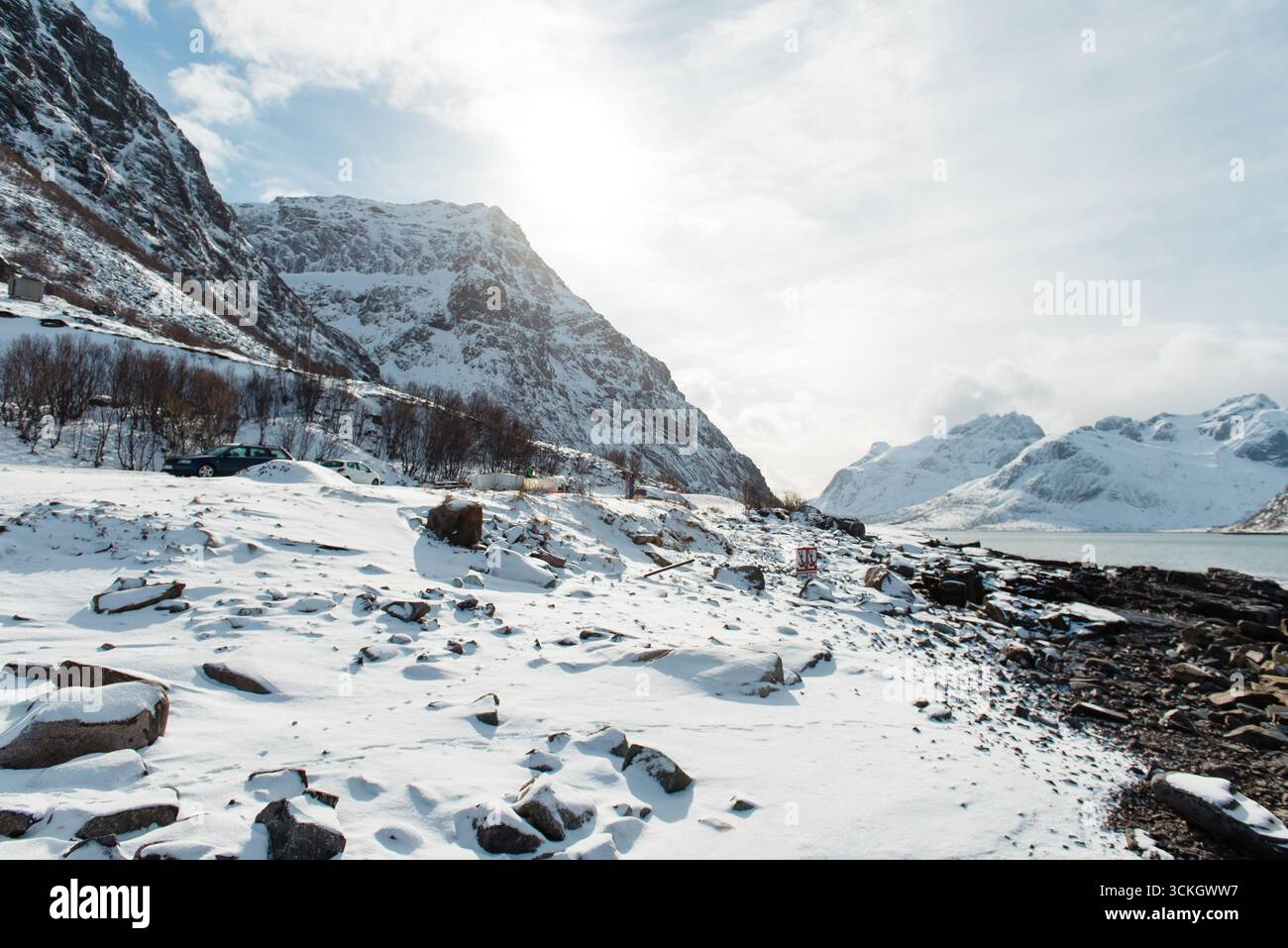 Schneebedeckte Berglandschaft mit felsiger Küste unter hellem Himmel. Stockfoto