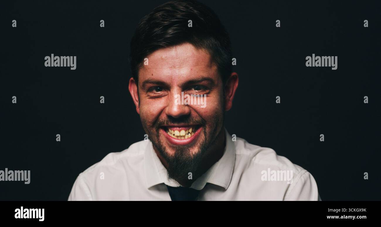 Porträt, Psychologie oder Mann im Studio mit bipolarem, dunklem oder isoliertem Hintergrund für psychische Gesundheit. Lachen, manisch oder in Not geratene Person mit Lächeln Stockfoto