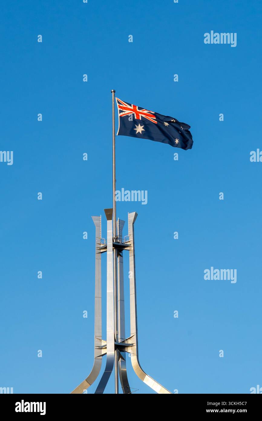 Die Flagge Australiens winkt mit blauem Himmel im Hintergrund auf dem Australia Parliament Building in Canberra, Australien. Stockfoto