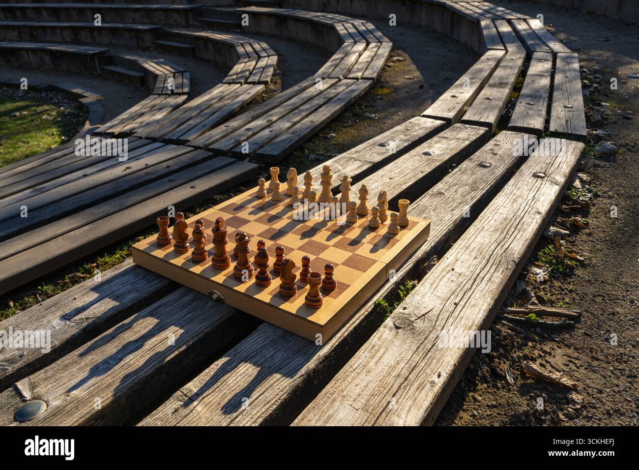 Schachbrett auf der Bank im Stadtpark, repräsentiert Outdoor-Erholung, Familienbindung, Quality Time und klassische Spiele, die in entspannender Natur genossen werden Stockfoto