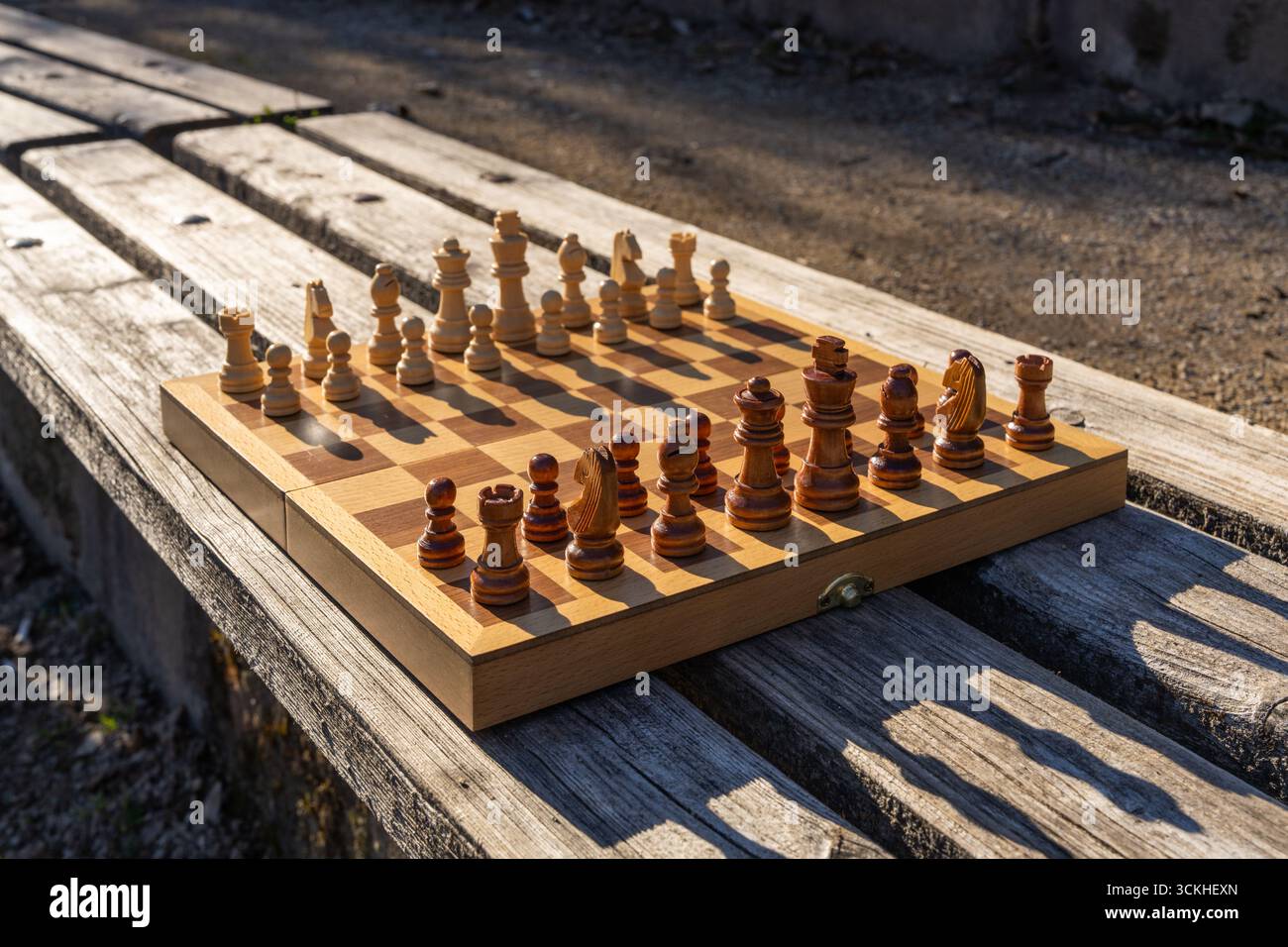 Urbane Parkszene mit Schachbrett auf Holzbank, die Erholung, Kultur und Achtsamkeit miteinander verbindet. Ein friedlicher Moment im Stadtleben mit Fokus auf Logik A Stockfoto