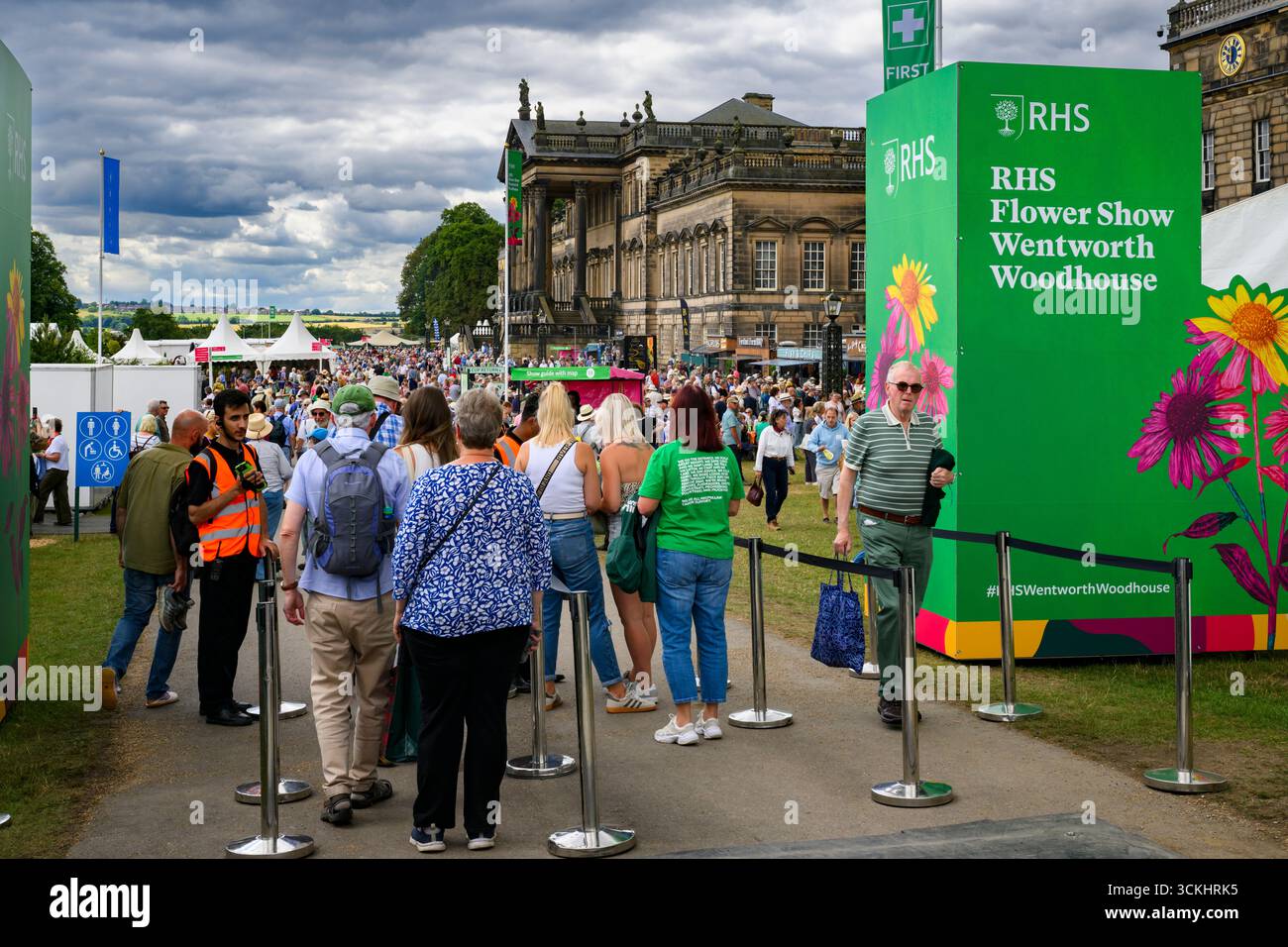 Leute kommen an und warten in der Warteschlange, Personal scannt Tickets, Herrenhaus & Schild - RHS Flower Show 2025, Wentworth Woodhouse, Yorkshire, England, Großbritannien. Stockfoto