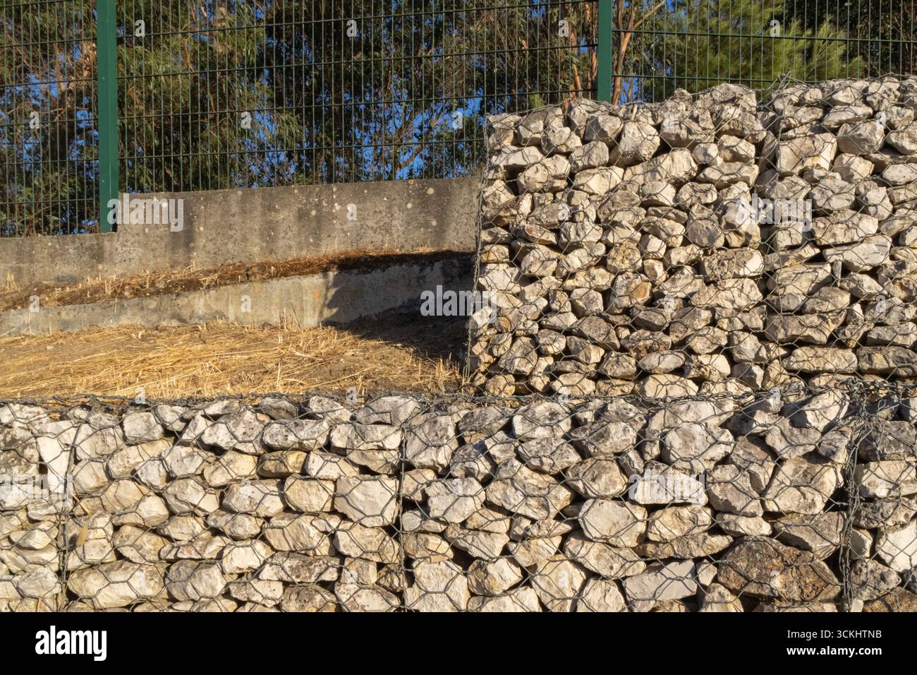 Stützwand aus mit Steinen gefüllten Gabionen, die Erosionsschutz und Hangstabilisierung bieten Stockfoto