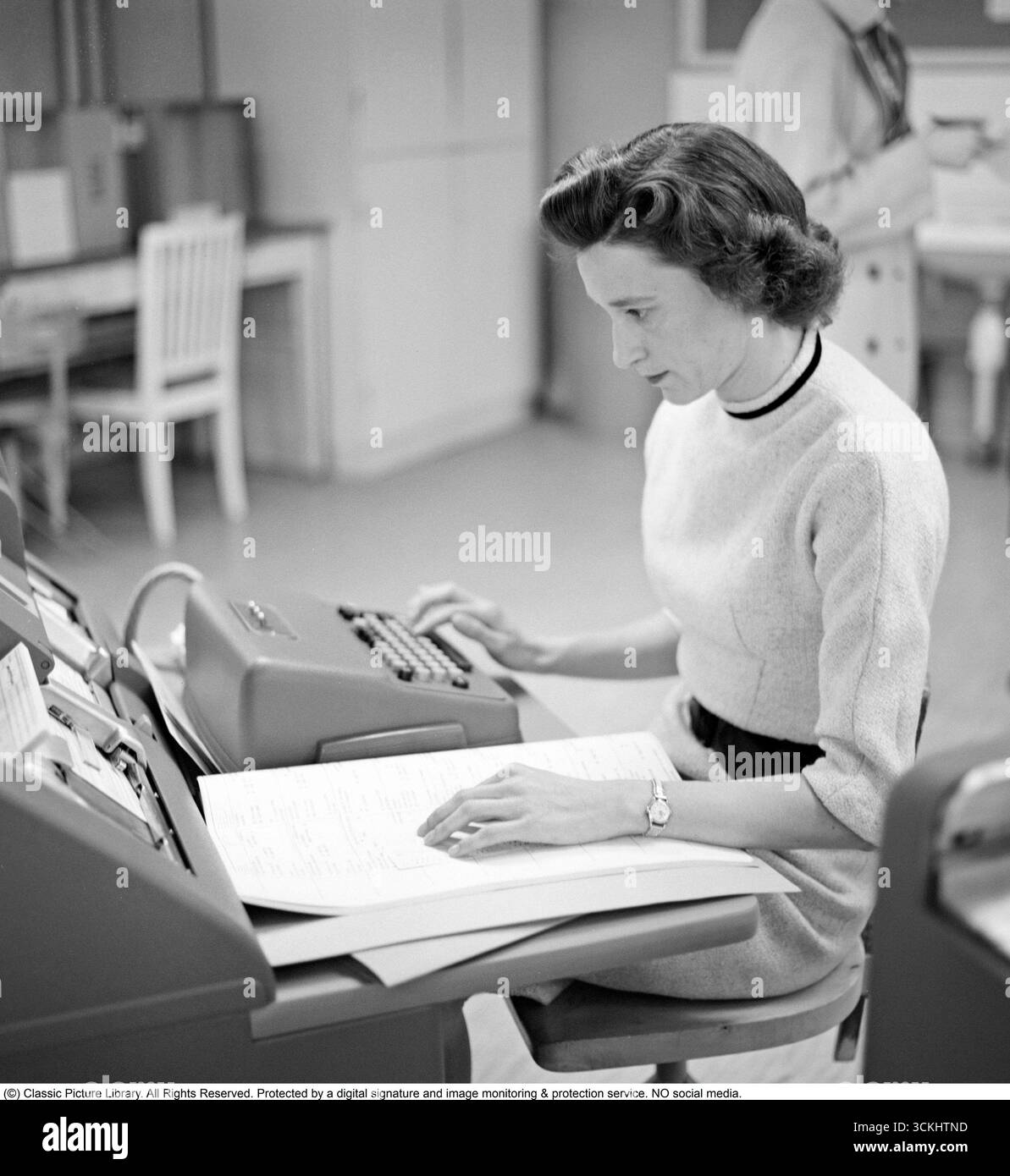 Junge Frau bei der Arbeit: An ihrem Schreibtisch kalkulieren, 1960 Eine Angestellte sitzt und zählt auf einen Taschenrechner. Kristoffersson Ref. CP47-2 Stockfoto
