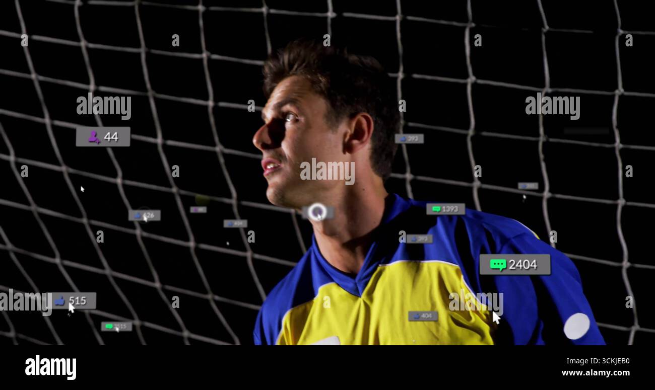 Stehender Fußballtorwart trägt blaues gelbes Trikot im nächtlichen Tornetz des Stadions mit digitalen Symbolen Stockfoto