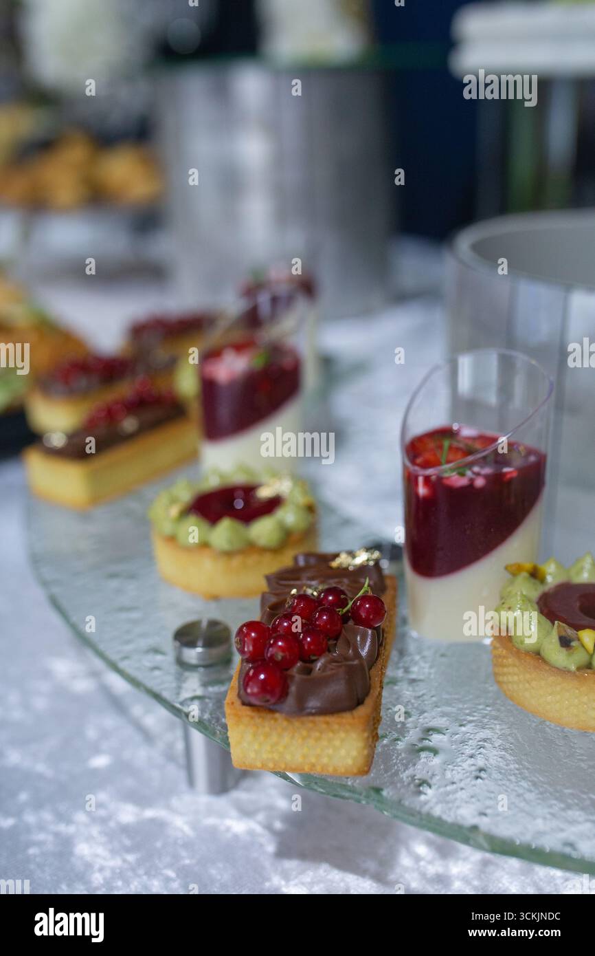 Elegante Desserts auf einem festlichen Tisch: Törtchen mit Beeren und Mousse in Gläsern. Anspruchsvolle Präsentation bei einer Veranstaltung oder Feier. Stockfoto