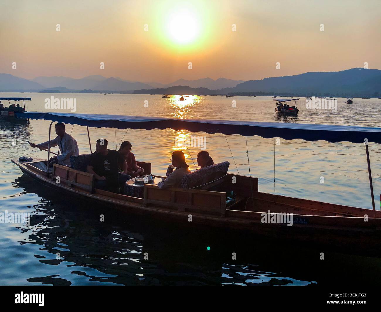 Hangzhou, China, Gruppenmenschen, Reiten im Boot, chinesische Touristen besuchen See im Stadtzentrum, Sonnenuntergang Scenic View Stockfoto