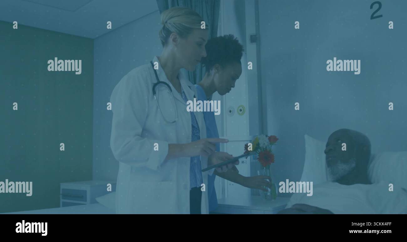 Die Patientennotizen auf der Tablette überprüfen, das medizinische Team in Uniformen platziert Blumen neben dem Bett auf der Station Stockfoto
