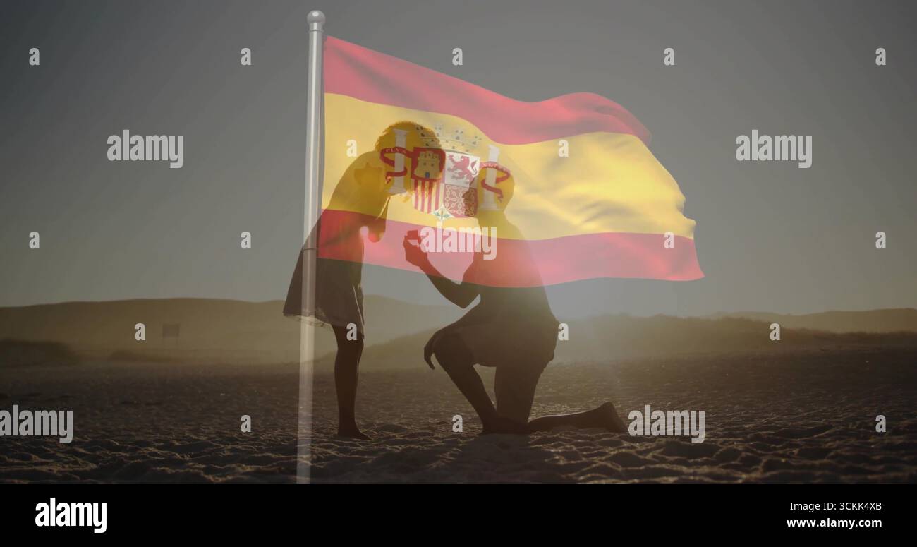 Ein Paar kniend am Strand bei Sonnenuntergang mit spanischer Flagge Stockfoto