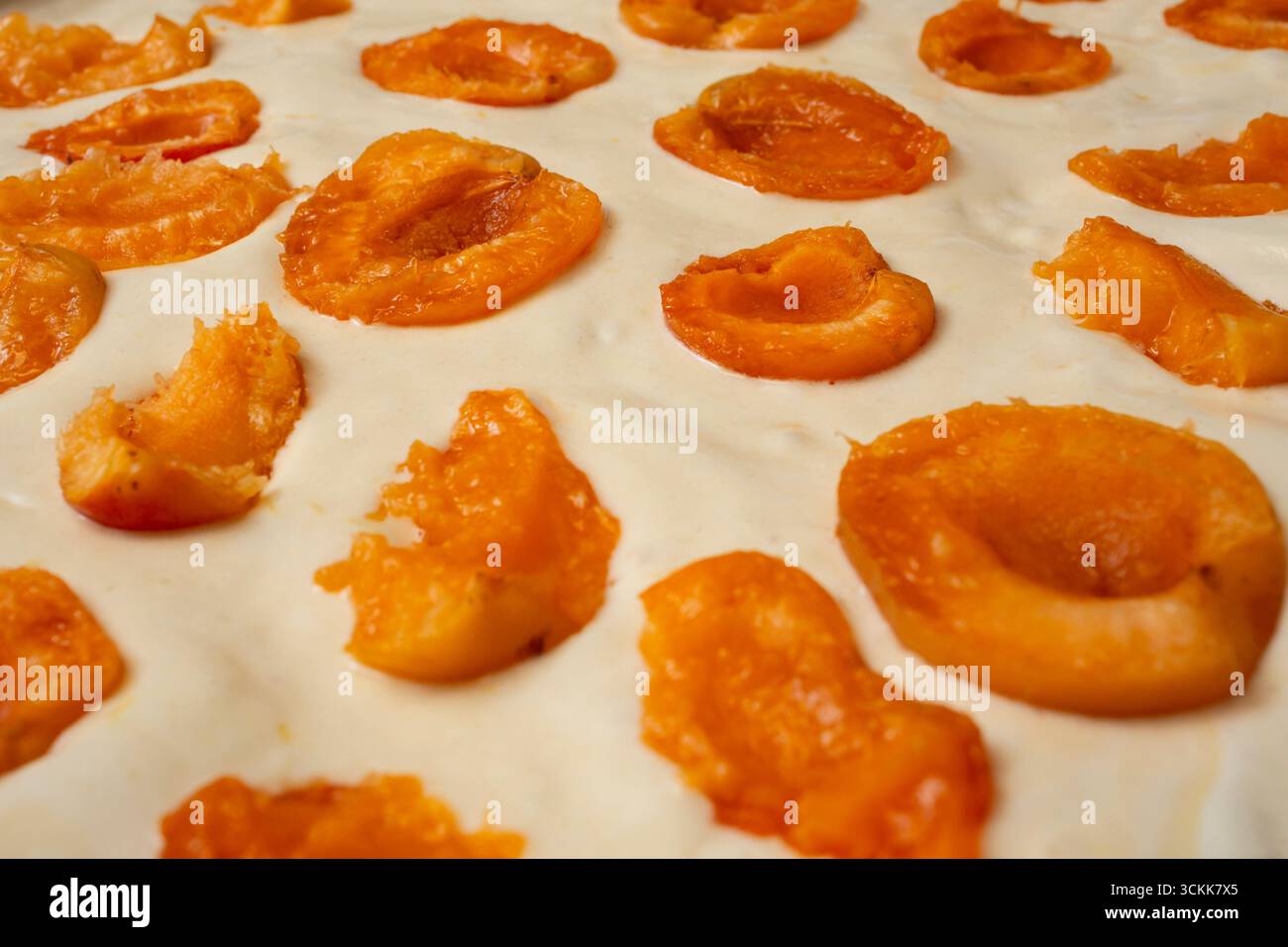 Roher Biskuitkuchen mit pfirsichfarbenen Hälften, Seitenansicht im Vollformat Stockfoto
