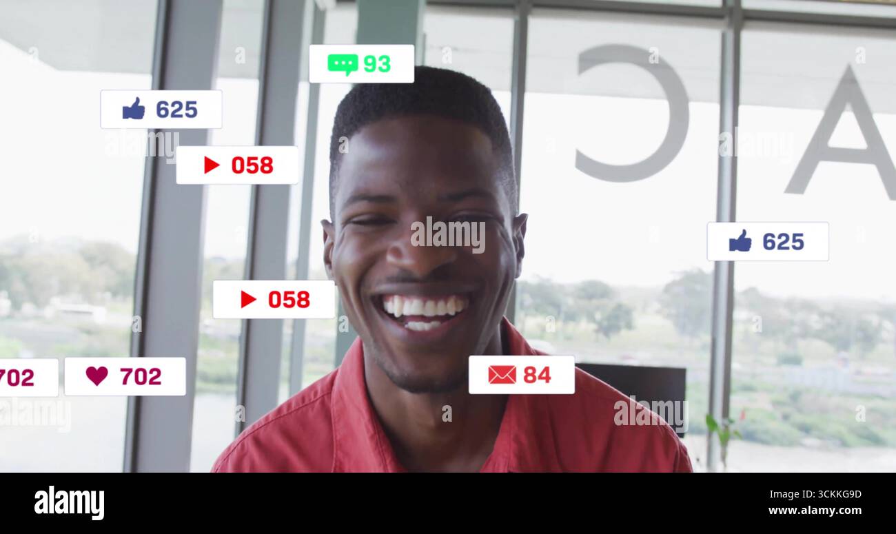 Ein lächelnder Gastgeber trägt ein rotes Hemd und steht an den Studiofenstern am Fluss, mit schwebenden sozialen Grafiken Stockfoto