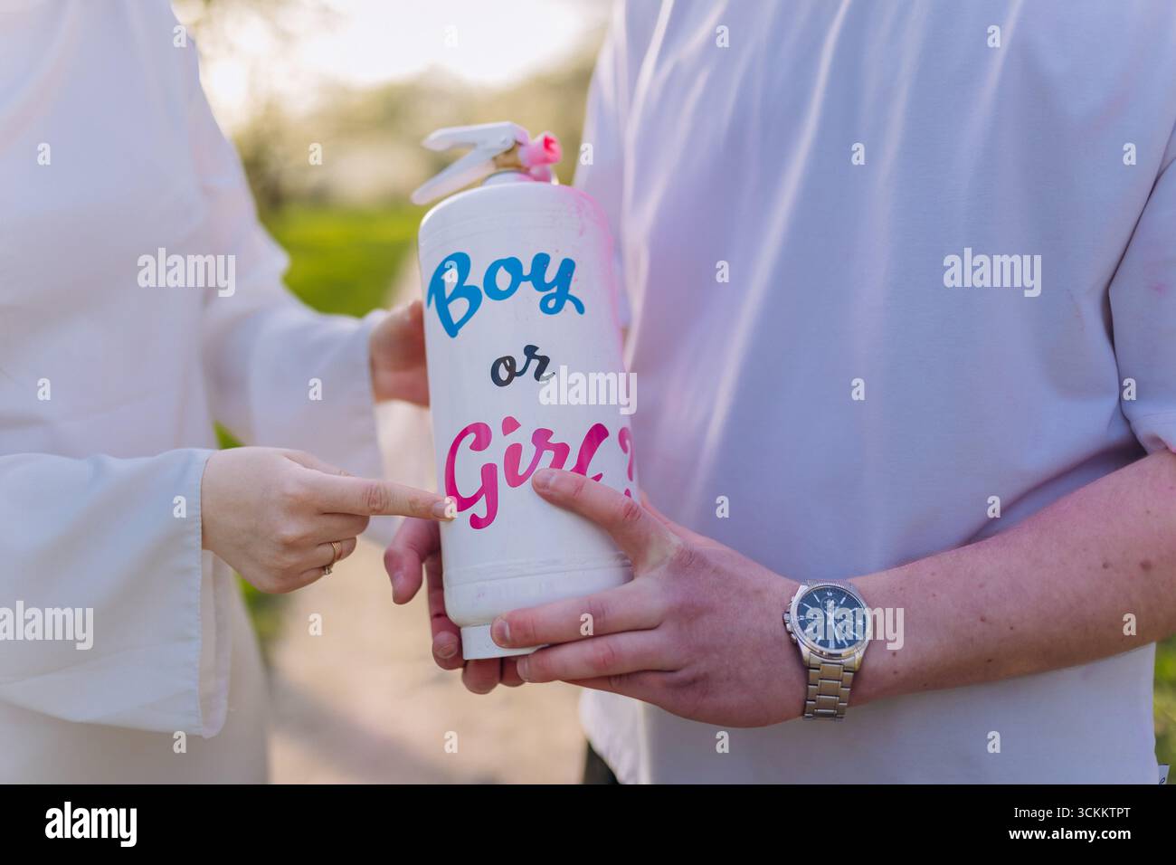 Paare, die das Geschlecht des Babys mit Farbspray während der Gender-Enthüllung-Feier im Freien enthüllen Stockfoto