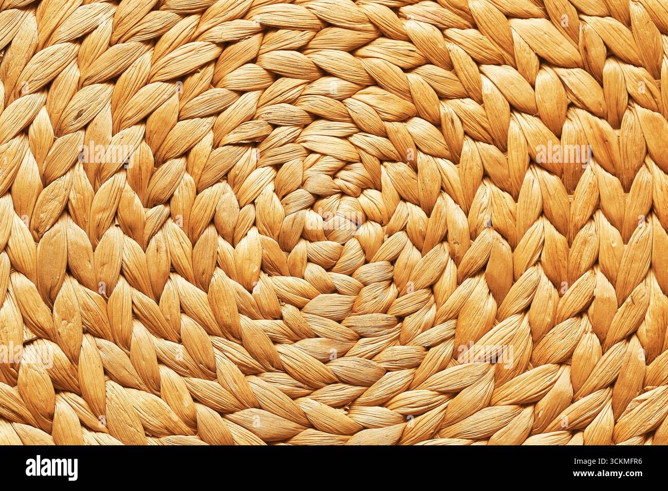 Hintergrund mit geflochtener Strohstruktur. Rund gewebte Oberfläche aus Naturmaterial. Rustikales handgefertigtes Basteldetail mit organischem Muster. Stockfoto